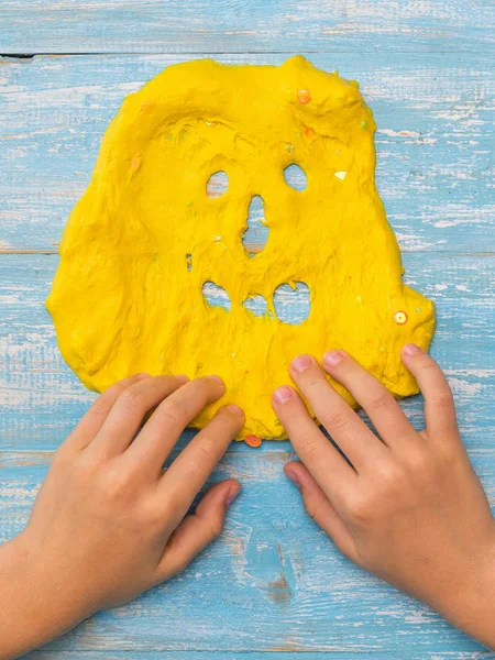 L'enfant dessine des dents sur un visage de boue jaune sur une table en bois . — Photo