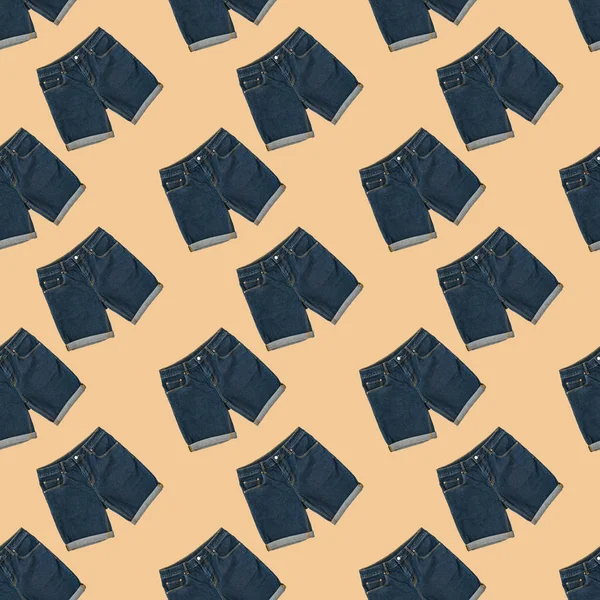 Nahtloses Muster blauer Jeans-Shorts auf beigem Hintergrund. Modische Unisex-Kleidung. — Stockfoto