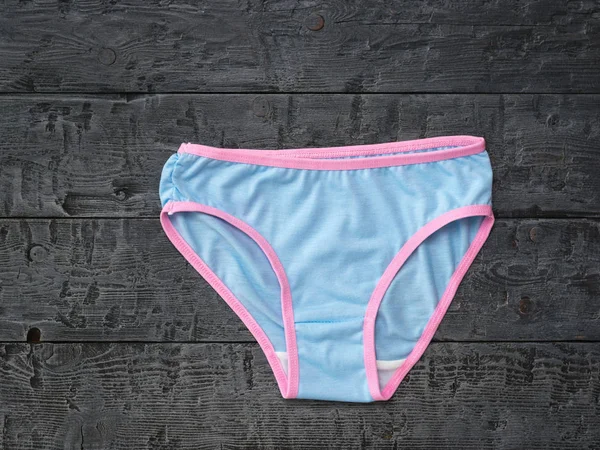 Blue women's panties with a red border on a black wooden table. Fashionable concept. Beautiful lingerie. The view from the top. — Stock Photo, Image