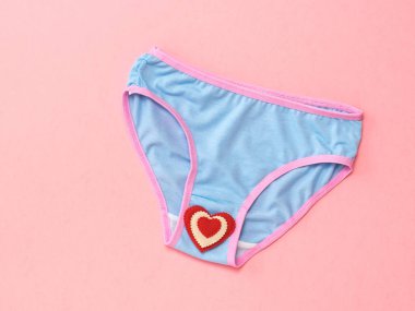 Pembe arka planda kırmızı ve beyaz kalpli mavi külot. Aşıklar buluşma kavramı. Iç çamaşırı. Yukarıdan görünüm.