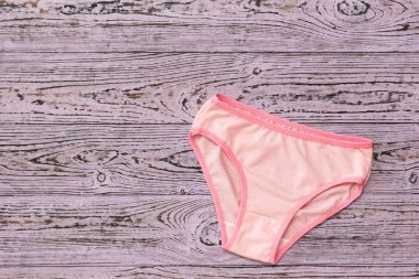 Ahşap arka planda kırmızı kenarlı pembe kadın külot. Modaya uygun bir konsept. Güzel iç çamaşırı. Yukarıdan görünüm.