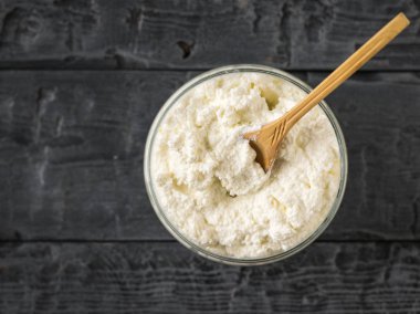 Rustik bir masada taze süzme peynir ile bir kavanozda tahta kaşık. Yukarıdan görünüm.