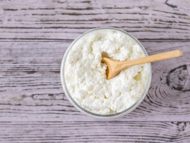 Rustik pembe bir masada taze süzme peynir ile bir kavanozda Tahta kaşık. Yukarıdan görünüm.