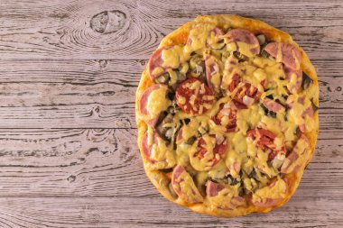 Ahşap bir masanın kenarında taze ev yapımı pizza. Yukarıdan görünüm.