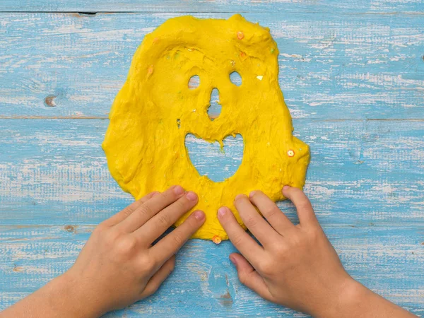 L'enfant fait un drôle de visage de boue jaune sur une table en bois . — Photo