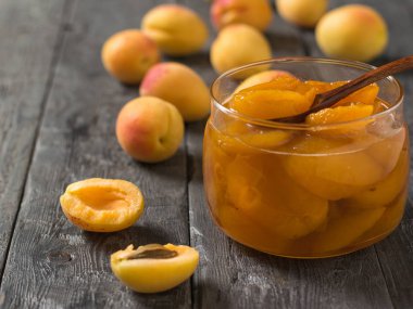 Ahşap bir masa üzerinde cam bir kavanozda olgun kayısı Reçeli.