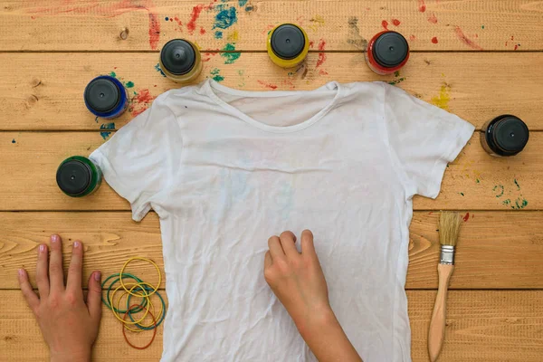 Flickan rullar upp en vit t-shirt för tillämpning av tie dye stil. — Stockfoto