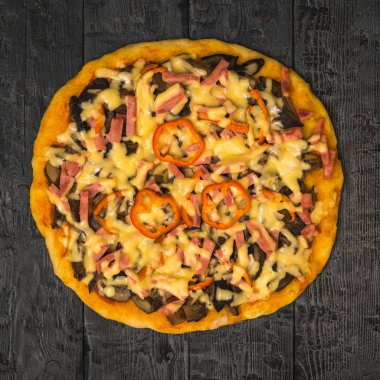 Ahşap bir masada Bulgar biberi ile dekore edilmiş büyük ev yapımı pizza. Yukarıdan görünüm.