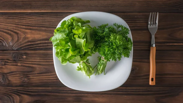 Verduras frescas em uma chapa branca e um garfo em uma mesa de madeira. Depósito plano . — Fotografia de Stock