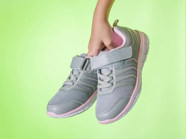 Fitness sneakers i barnets hand på en grön bakgrund. Färg trend. — Stockfoto