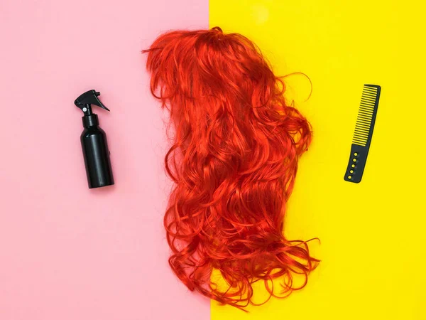 Lacca per capelli, pettine nero e parrucca arancione su sfondo bicolore. Accessori per creare stile . — Foto Stock