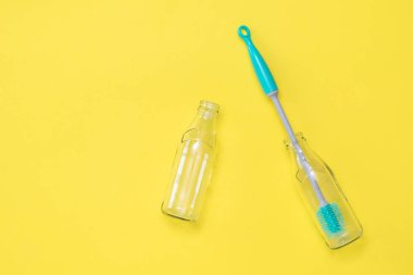 Şişe yıkama fırçası ve boş şişeler sarı arka plan üzerinde.