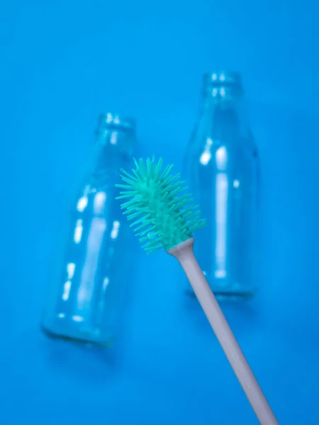 Bottle washing brush and empty bottles on dark blue background. — Stock Photo, Image