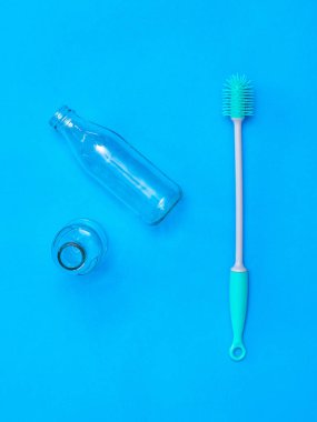 İki cam şişe ve mavi arka plan üzerinde bir yıkama fırçası.