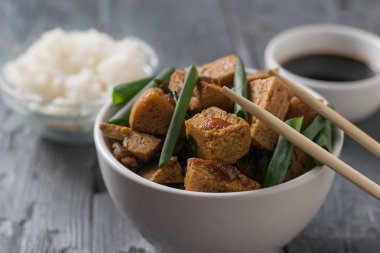 Ahşap bir masada pirinç ve soya sosu ile rosto tofu peyniri.