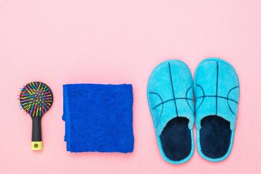 Mavi Terlik, havlu ve tarak pembe arka plan üzerinde.