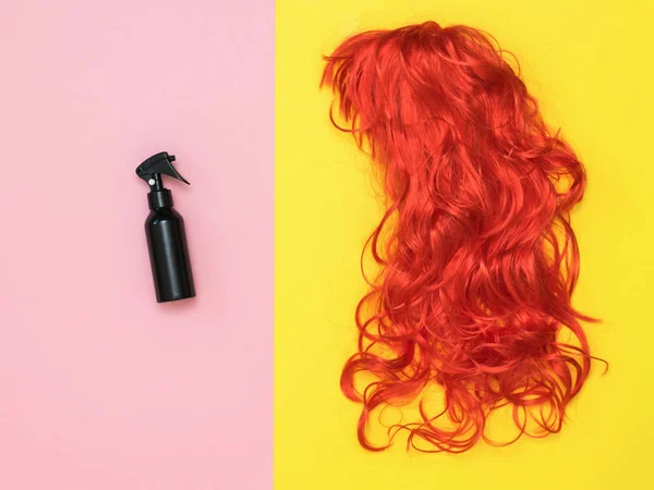 Flacone spray per capelli nero e parrucca arancione su sfondo rosa e giallo. Accessori per creare stile . — Foto Stock