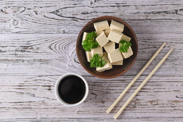 筷子和豆腐芝士放在木制桌子上的黏土碗里. 大豆芝士。 平躺着. — 图库照片