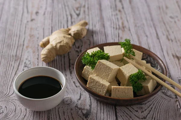 Tofu cheese, soy sauce and ginger root on a wooden table. Soy cheese. — Stock Photo, Image