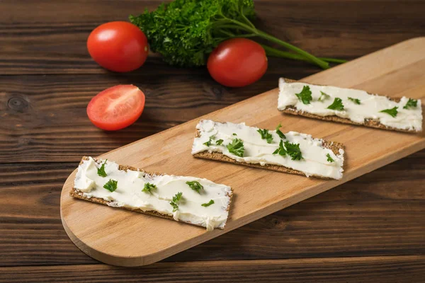 Bread toast with cheese, herbs and tomatoes on a wooden table. Vegetarian snack.