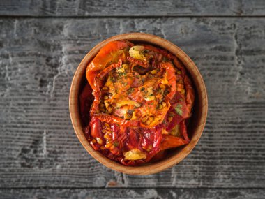 Ahşap bir masanın ortasında, tahta bir kasede kurutulmuş domates. Vejetaryen yemeği. Düz yatıyordu.