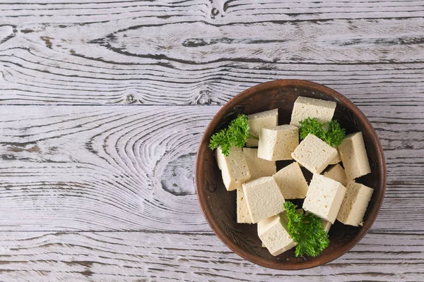 Persil avec tranches de tofu dans un bol en argile sur une table en bois. Du fromage de soja. Pose plate . — Photo