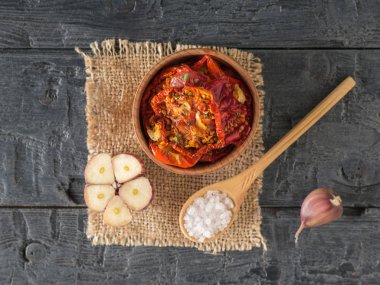 Çuval bezinde tahta kaşıkla ahşap bir kasede fırında domates. Vejetaryen yemeği..