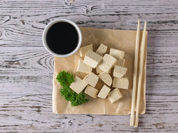 Un trozo de papel arrugado con salsa de soja y rebanadas de queso tofu. Queso de soja. Puesta plana . — Foto de Stock