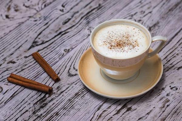 Secangkir kopi segar dengan tongkat kayu manis di atas meja kayu . — Stok Foto