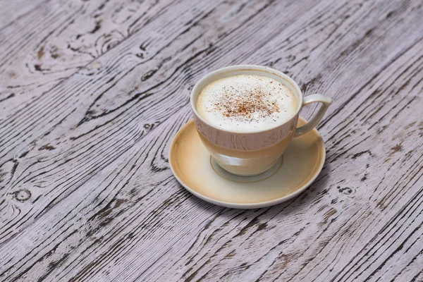Una taza de café perfumado con leche y canela sobre una mesa de madera . — Foto de Stock