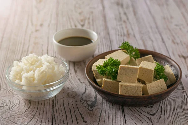 Tofu avec sauce soja et riz sur une table en bois au soleil . — Photo
