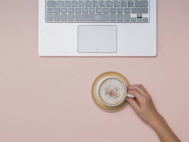 Elinde kahve fincanı ve arka planda dizüstü bilgisayarla. Görev.