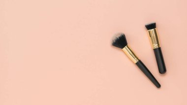 Pastel arka planda iki makyaj fırçası..