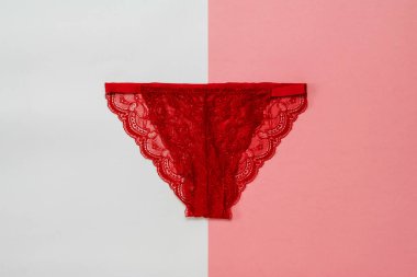 Beyaz ve kırmızı arka planda parlak kırmızı kadın külotu. İç çamaşırı. Yukarıdan görünüşü.