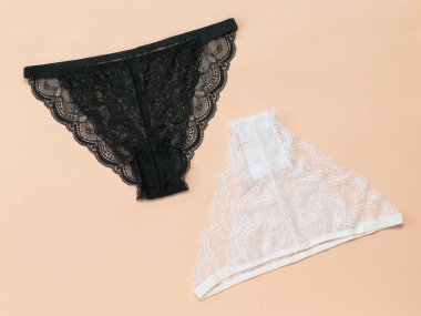 Pastel arka planda beyaz ve siyah kadın külotu. Düz yatıyordu.