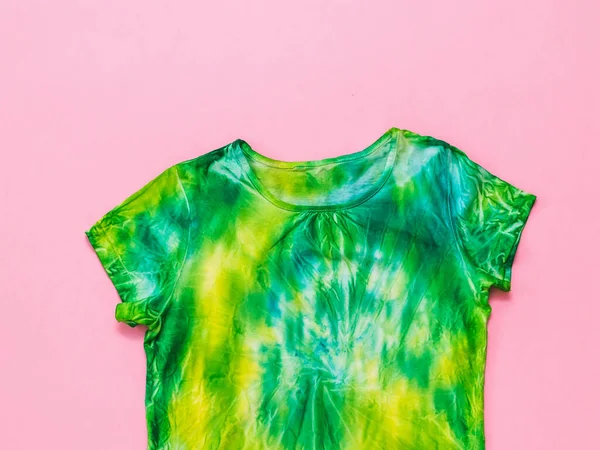 T-shirt amarela e verde em estilo tie dye em um fundo rosa claro. Depósito plano . — Fotografia de Stock