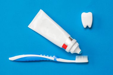 Diş macunu tüpten çıkıp mavi arka plandaki diş fırçasına akar. Düz yatıyordu.