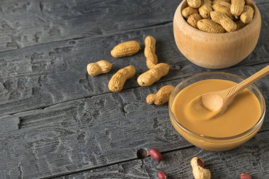 Tahta bir masada fıstık ezmeli, fıstık ezmeli cam kase..