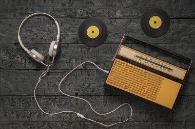 Retro radyo, kulaklıklar ve ahşap arka planda sarı vinil diskler. Geçmişteki radyo mühendisliği.