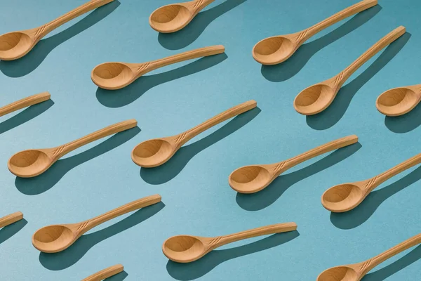 Background of a large number of wooden spoons on a blue background. — Stock Photo, Image