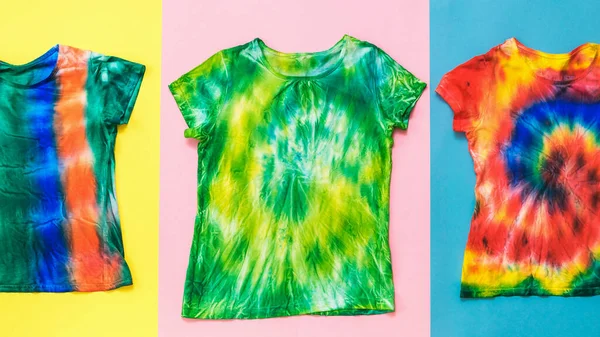 Een set van tie dye t-shirts op een veelkleurige achtergrond. Vlakke plaat. — Stockfoto