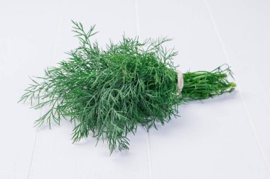 Beyaz ahşap bir masada taze toplanmış dereotlar..