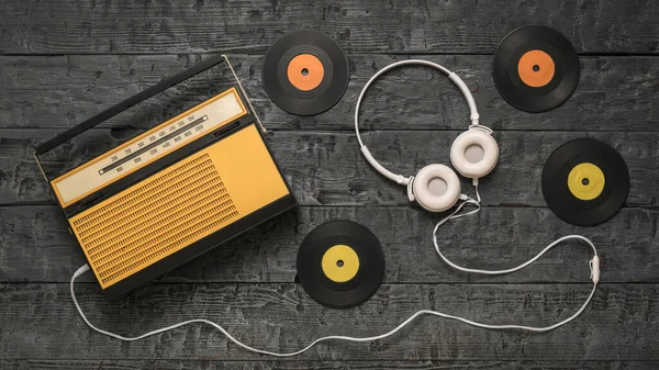 Dört vinil disk, bir radyo ve ahşap bir arka planda kulaklık. Geçmişteki radyo mühendisliği. — Stok fotoğraf