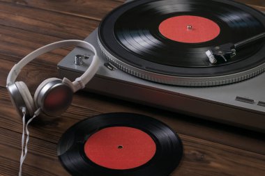 Beyaz kulaklıklar ve ahşap bir arka planda plak çalar..