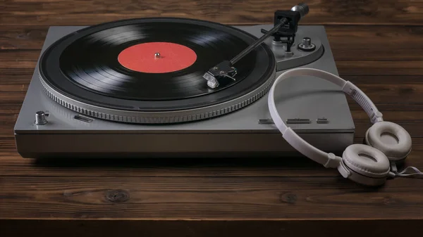A vinyl record player and headphones on a wooden table. — Stock Photo, Image