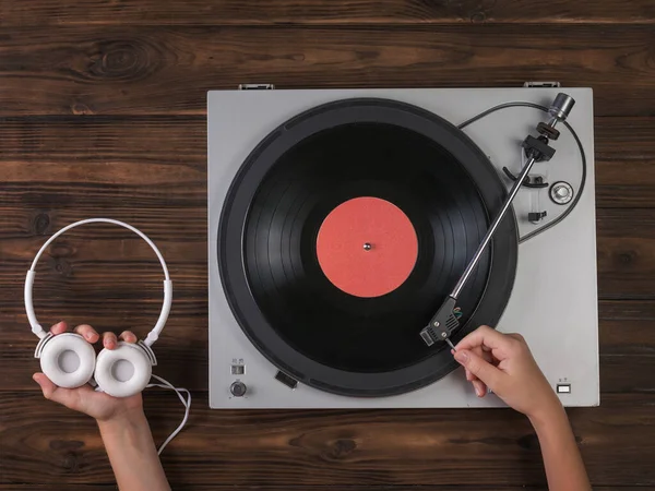 Hands hold white headphones and place a vinyl disc on the player. — Stock Photo, Image