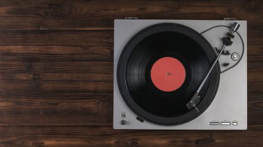 Kahverengi ahşap arka planda vinil plak çalar. Yukarıdan görünüşü.