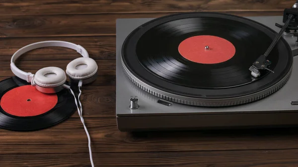 Bílá sluchátka s drátem jsou připojena na vinylový diskový přehrávač. — Stock fotografie