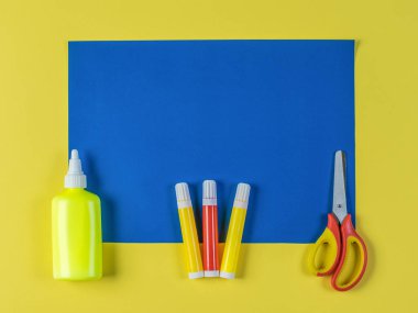 İşaretler, yapıştırıcı ve makas ile sarı arka planda mavi bir kağıt..