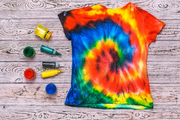 Die Rückseite einer Krawatte färbt ein T-Shirt auf einem Holztisch mit Farbe. Flache Lage. — Stockfoto